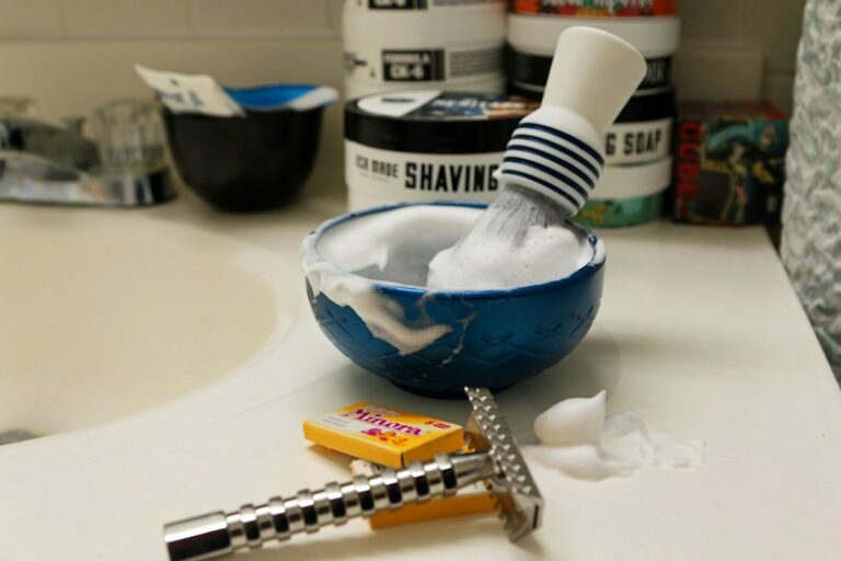 Shaving brush, bowl of lather, and razor on a bathroom sink